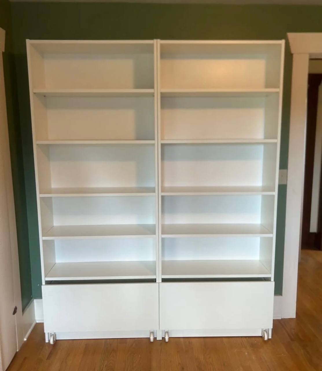 Two tall white bookcases with bottom drawers assembled side by side by 24 Solve in Seattle