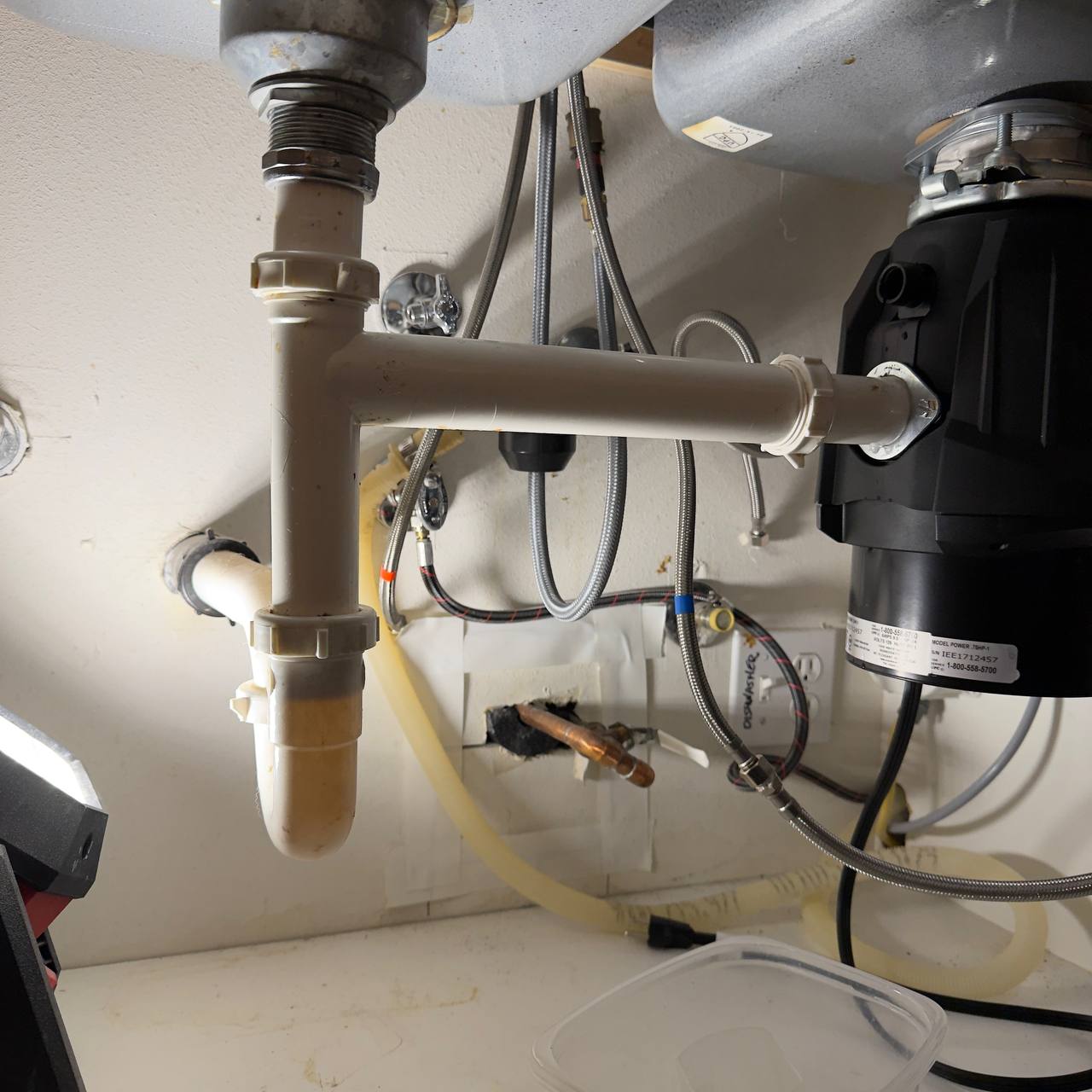Under-sink plumbing setup with pipes and junction box.