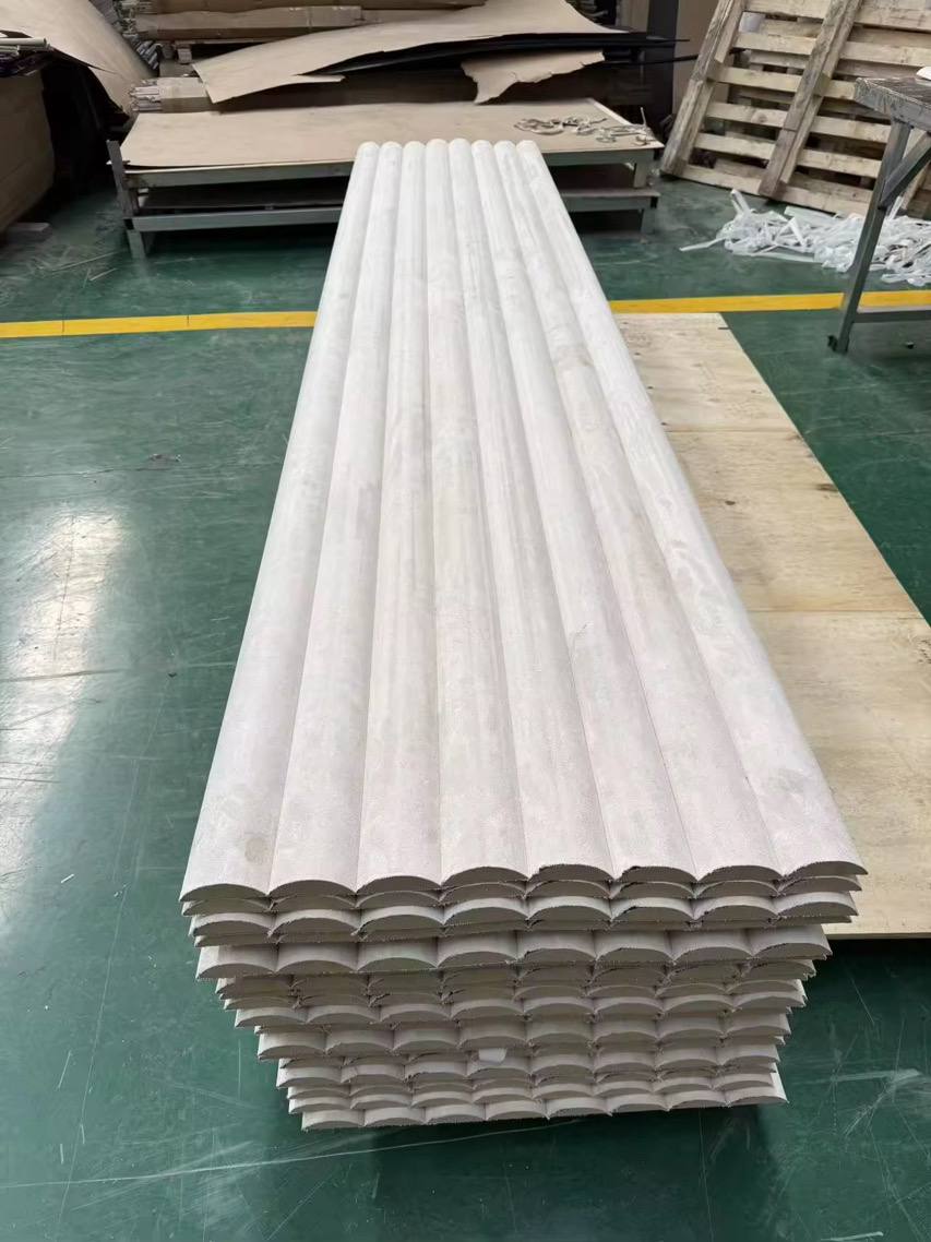 Stack of white corrugated panels on a green floor with wooden pallets in the background